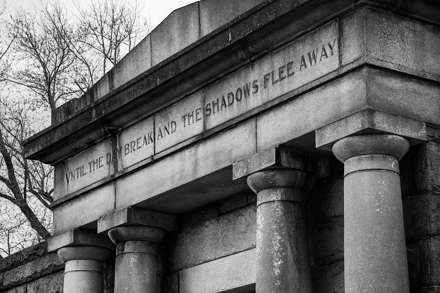 black and white photo of a tomb with the lettering until the day break and the shadows flee away chiseled into the stone
