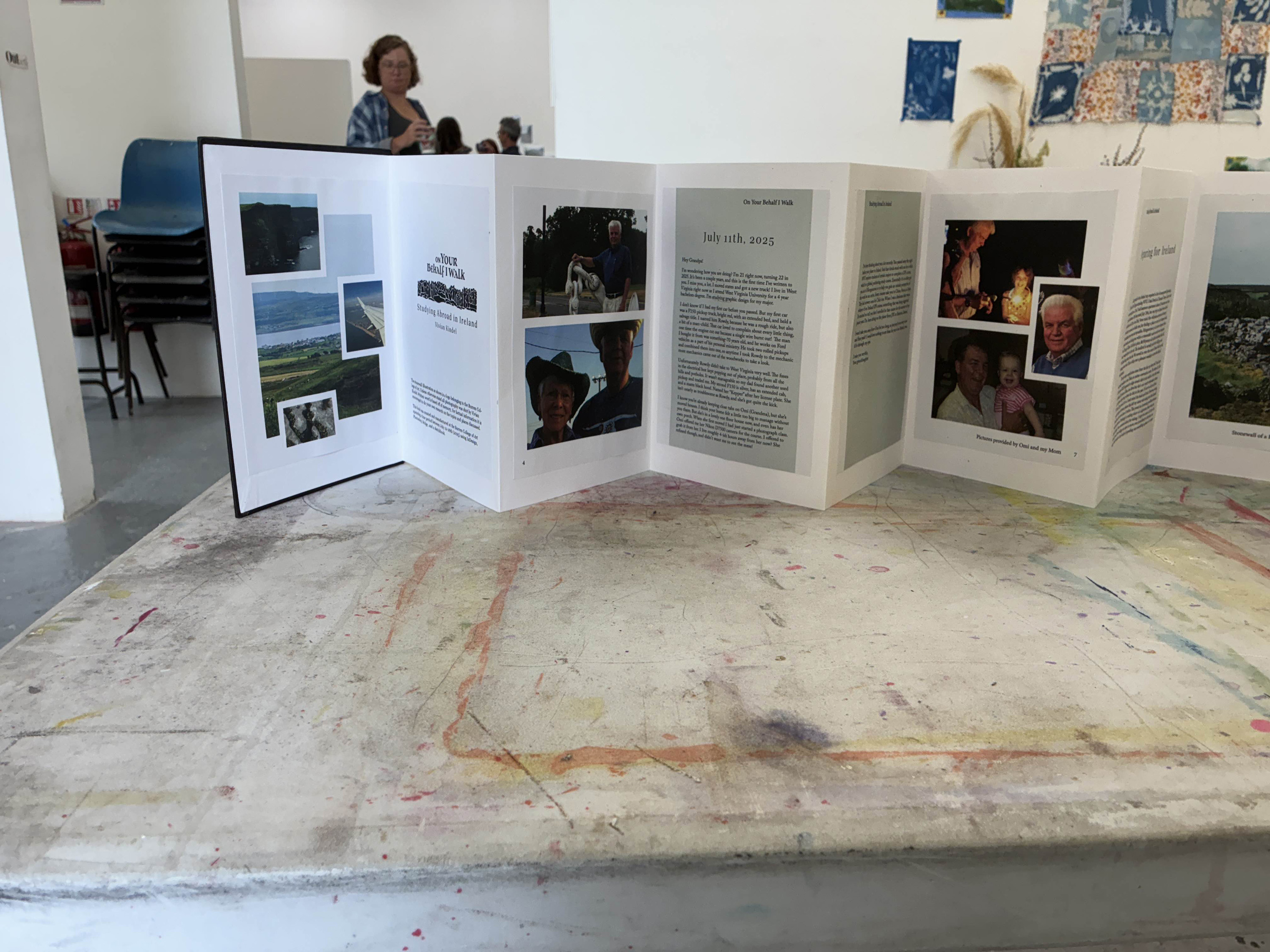 a photograph of an accordion fold book standing on a tabletop. The book displays photographs and written-text created by vivian. The book letters she addresses to her deceased grandfather, telling him of her personal thoughts and travels of her time in Ireland as well as photographs she took while studying abroad