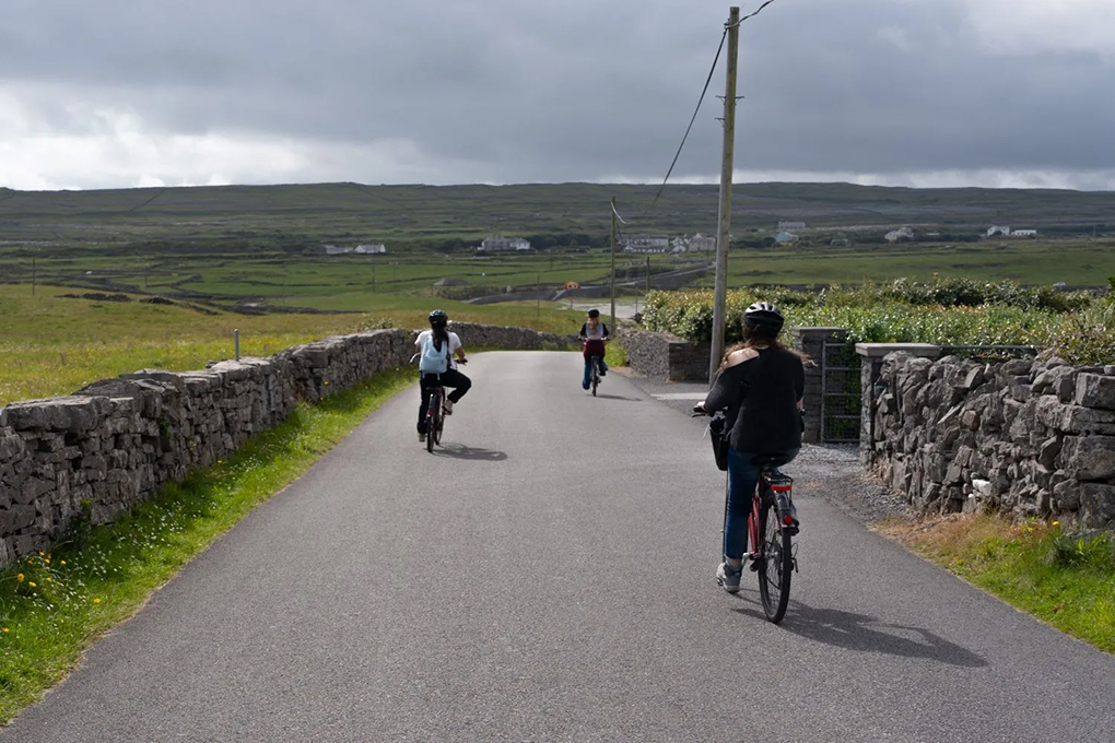 colored photograph of vivian kindel riding a bike in ireland landscape